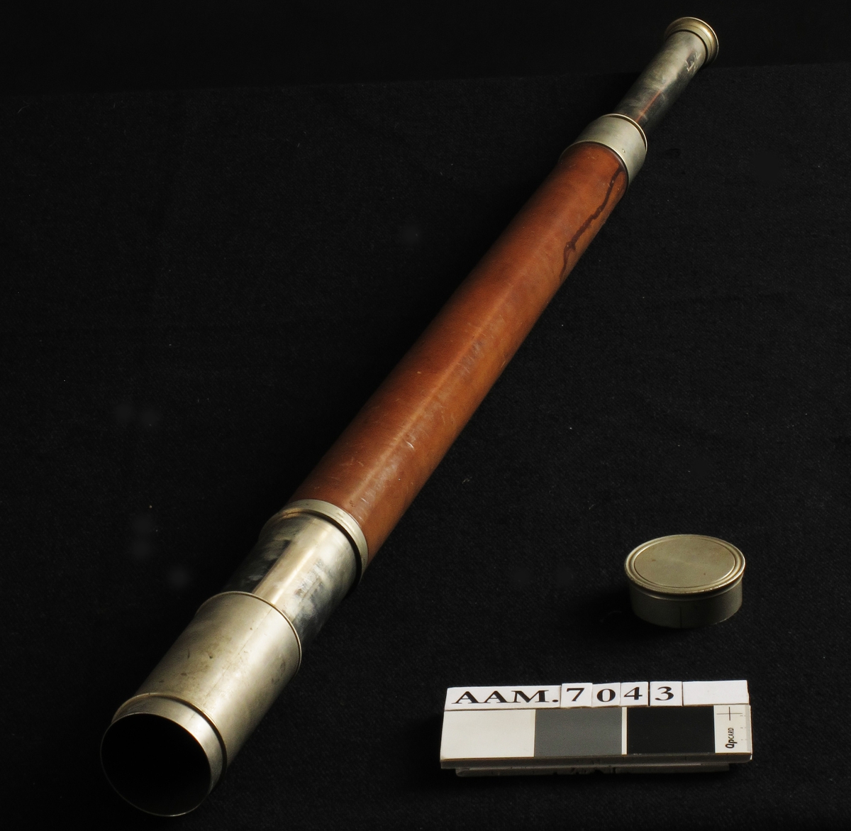 Langkikkert,  laget av  Troughton & Simms, London, 1863.  
a) Kikkert.   Forkrommet   metall,  brunt skinn. Lang sylinder med forkrommet del i hver ende, kanelbrunt skinn pm.  Når den smale ende trekkes ut, kommer flg. tekst til syne: 

" Presented by the British Government to Captain J. M. Smith, Master of the Norwegian Barque "Solon" of Arendal,   in acknowledgement of his humanity and kindness to the   Master and Crew on the Barque "Lemuel" of Souht Shields,  whom he rescued from their sinking Vessel on the 22nd   September 1863."  Under: " Troughton & Simms, London."  

b) Etui.   Mahogni  med litt grønn filt.  Langt etui med flatt lokk og to   messing  kroker i siden. Nedsenket felt med avskårne hjørner midt på lokket,  har vært pålimt etikett med tekst iflg. protokoll: Captain J. M. Smith. 

Tilstand febr. 1967: kikkerten god. Etuiet en del oppskrapet i toppflaten.