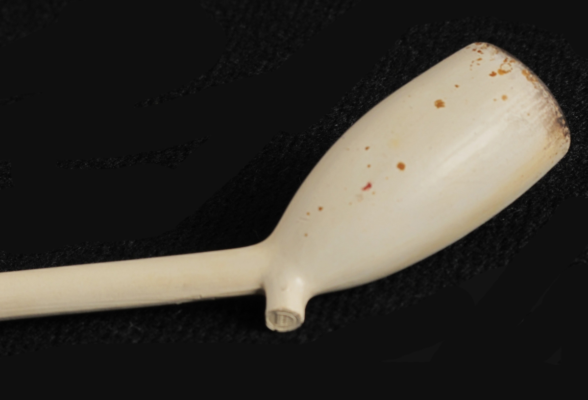 Krittpipe, hollandsk type, siste 3. del 1600 t.  Smalt hode, like bredt oppe som nede, med stor oval ståflate, tykt  kort skaft, avbrukket. Uten stempler.