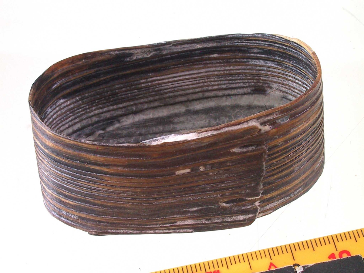 Liten oval eske (ask), Sveipet av tre. Oval bunn, rettsidet eske, lokk mangler.  Lå inni den større ovale esken med  myntene, knapper, de to signeter m. m.