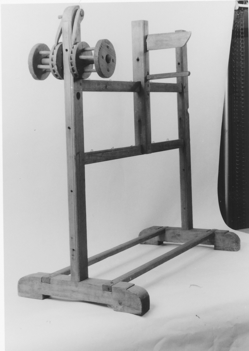 På den ene sidestolpen 1 tannhjul, med stopper på hver side, på midtstolpen 2 pinner, den ene med hakk øverst.