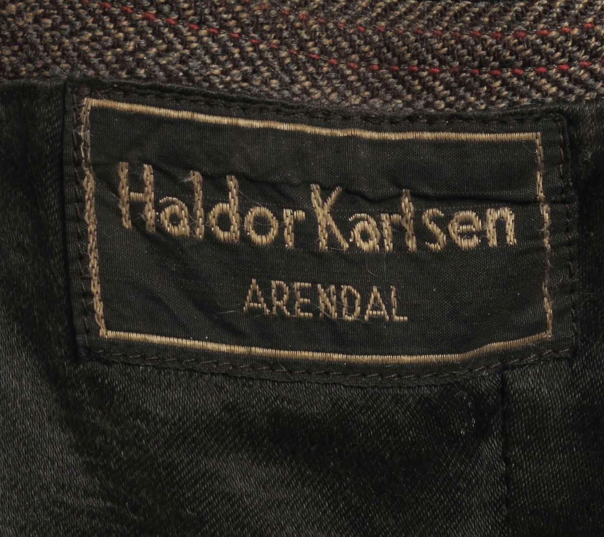 Stipet stoff, krisevare produsert under 2.verdenskrig, blanding av ull og cellull, som ble laget av cellulose. Foret var gammelt - enten noe de hadde liggende, eller sprettet av gamle klær.  Snittet er litt spesielt, trolig for å utnytte små biter stoff.