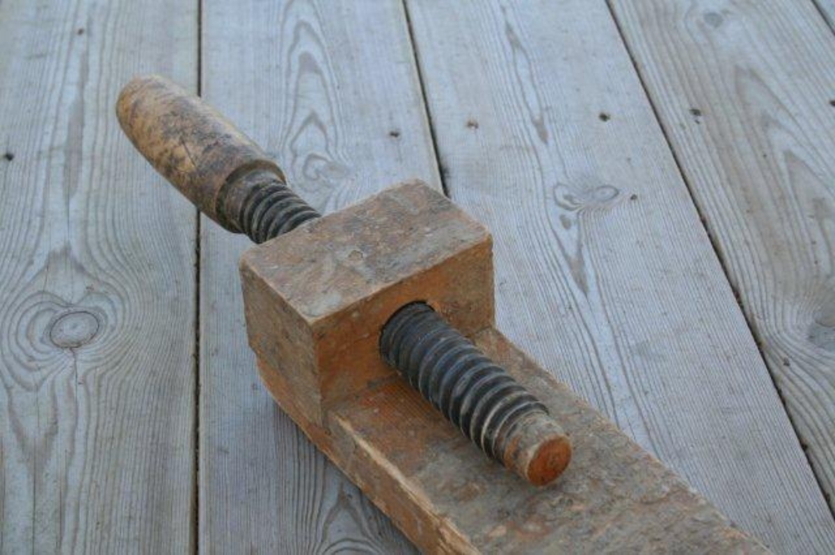 Lang arm med syv hull. Fast endeknekt med spindel (skrue). Motknekt i form av tapp  som kan flyttes fra hull til hull.