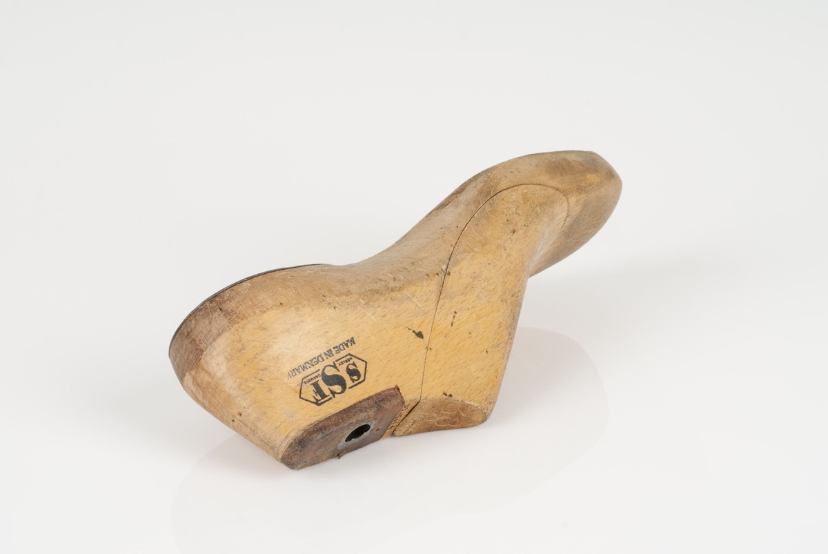 En tremodell i to deler; lest og opplest/overlest (kile).
Høyrefot i skostørrelse 38, og 8 cm i vidde.
Hælstykket i metall.