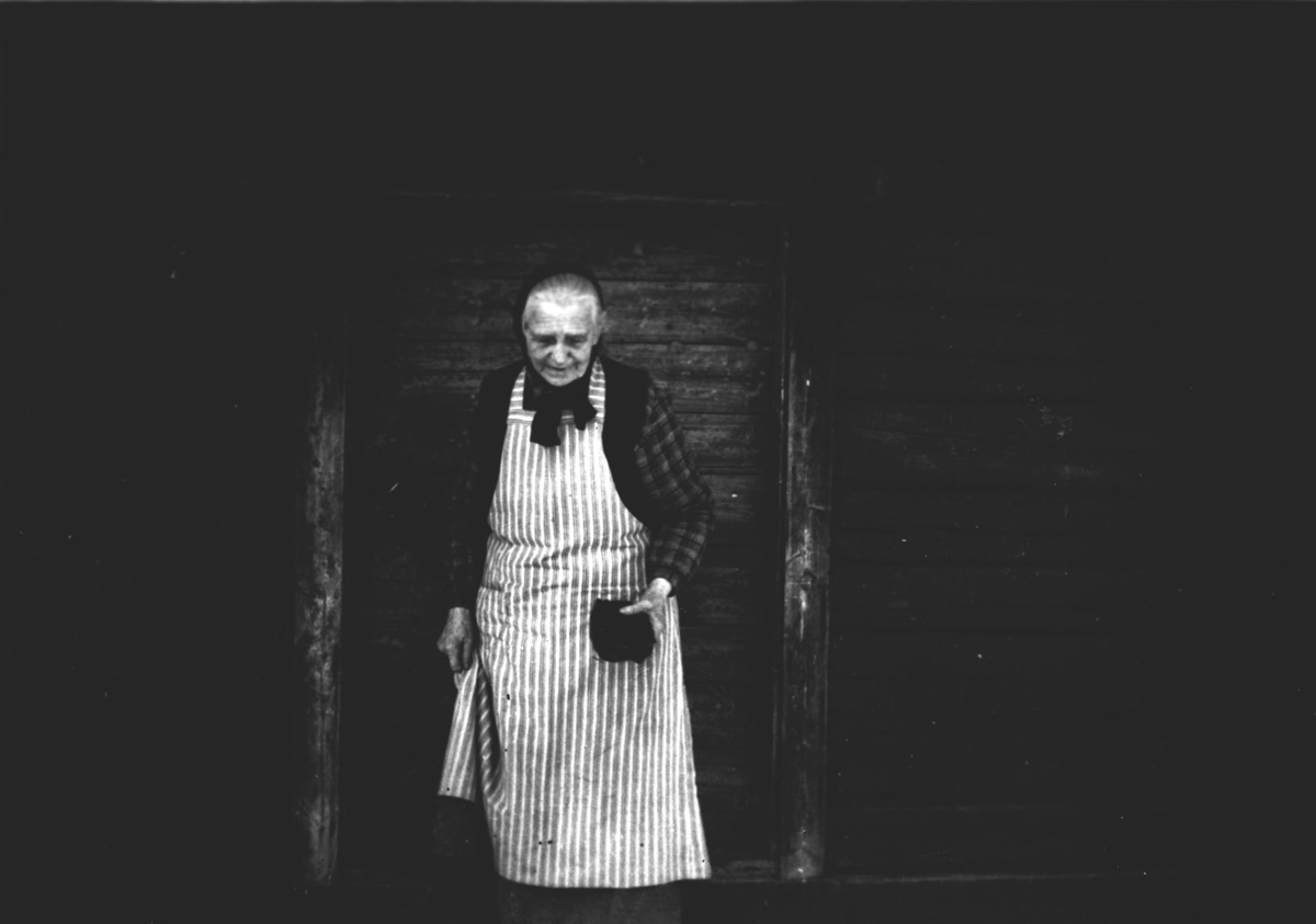 Eldre kvinne på stabburstrapp.