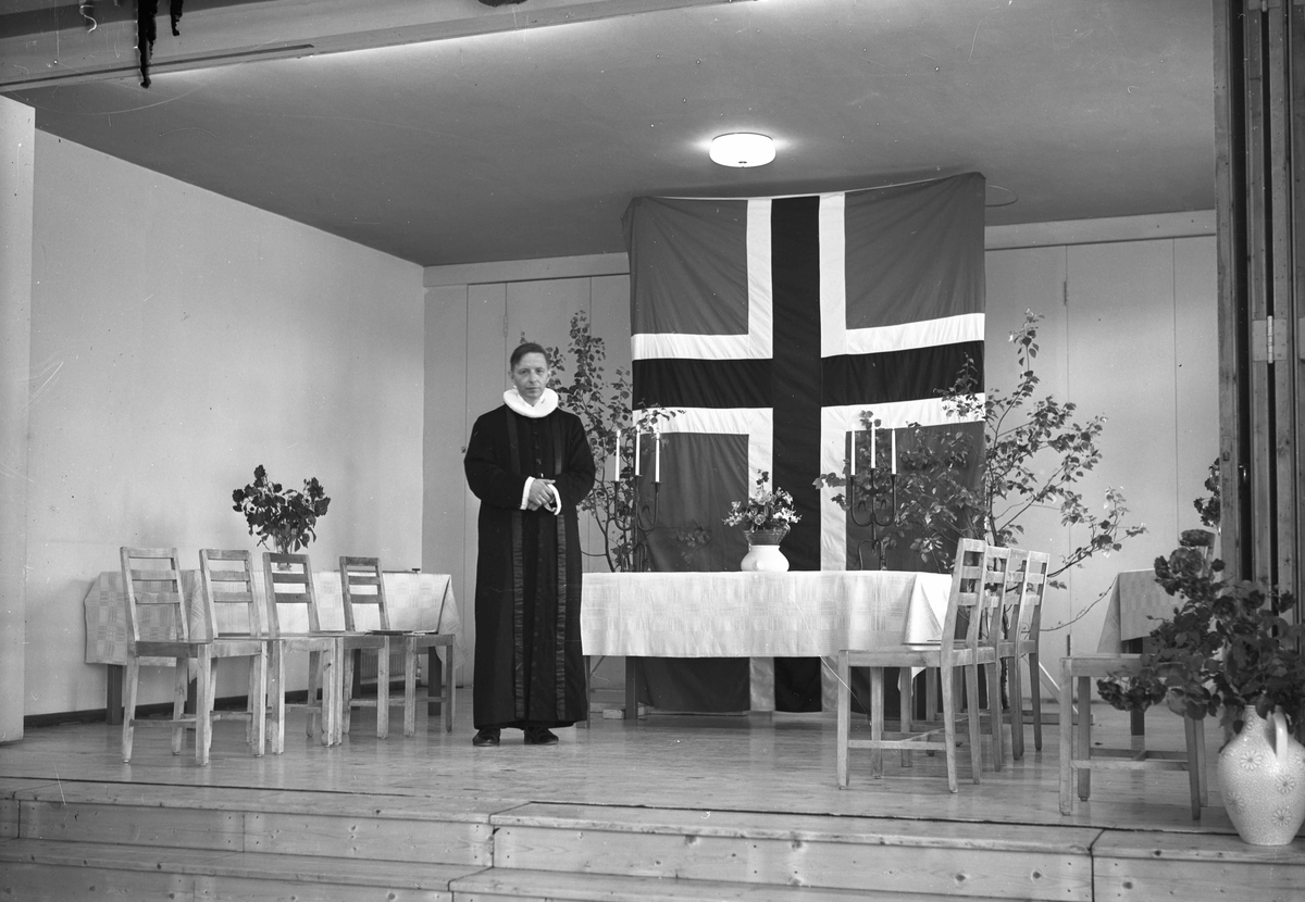 Prest foran flagg.