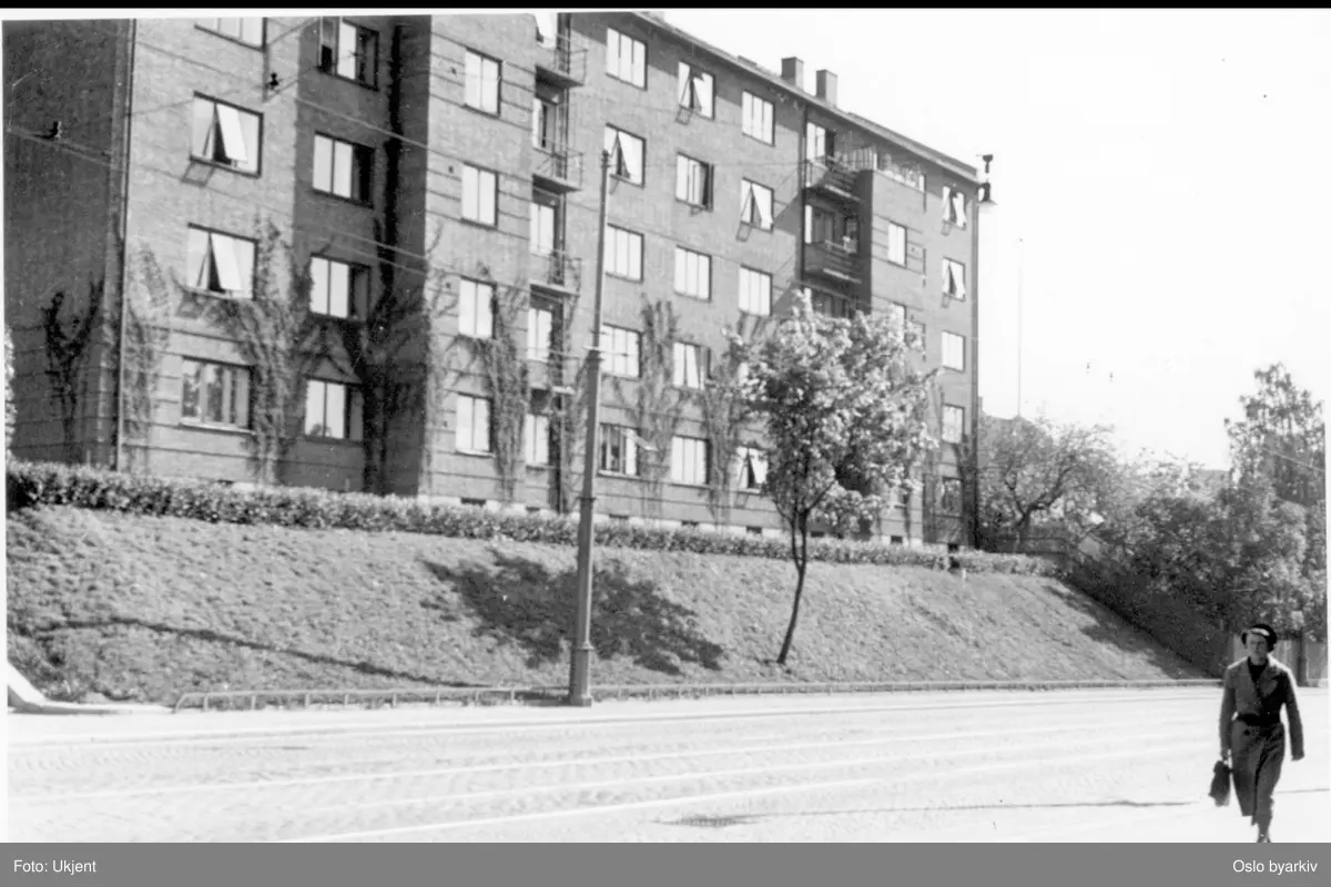 Boligblokk med forhage med platåhekk og skråning ned mot fortau. Arendalsgata i forgrunnen.