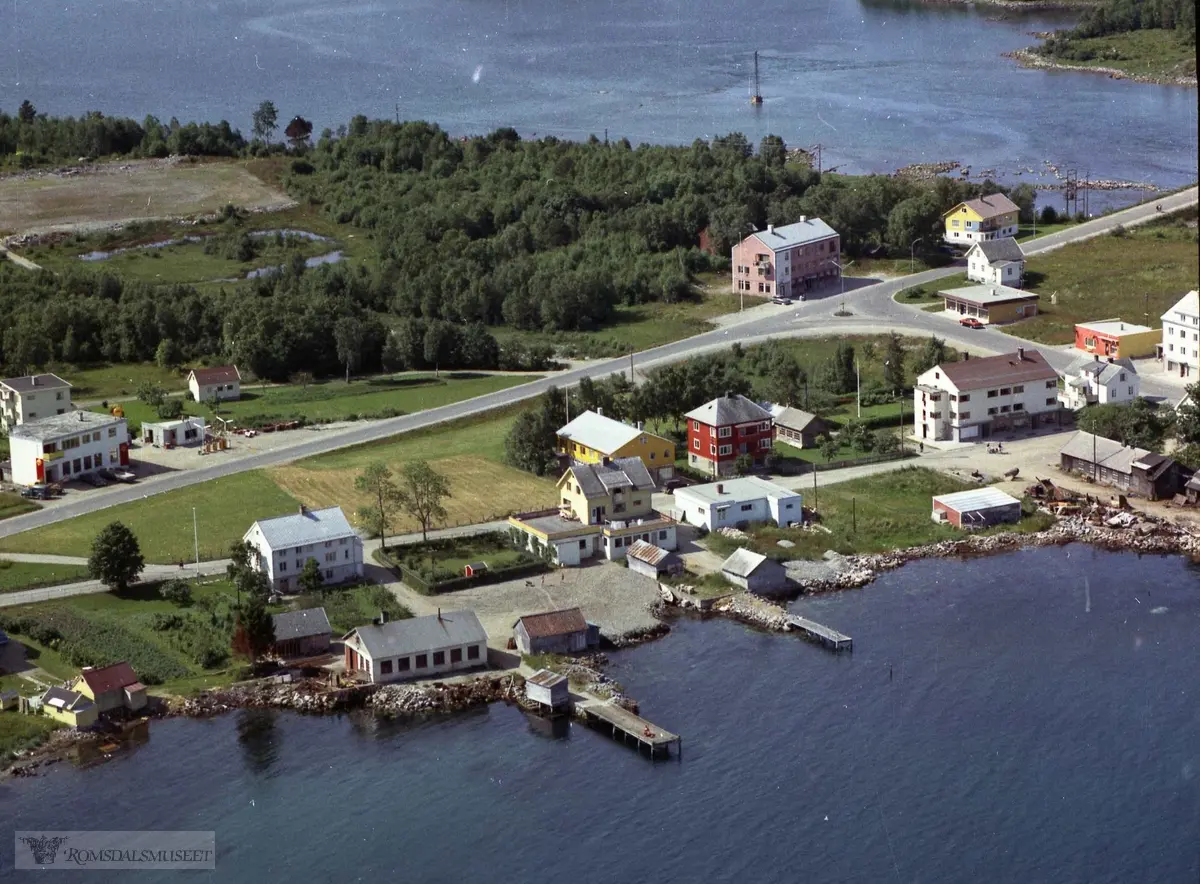 Helland øvre, gnr. 46..1. Sanert bygg. Eigedommen til Konrad Vestnes..2. Sanert bygg. John Bruteig hadde bilverkstad, bensinstasjon og bustad her..3. Bnr. 52 .Vestnes sparebank sitt nybygg frå 1958. Seinare Sparebanken Møre.   .4. Sanert bygg. Alfred Sivertsen sitt hus. I undeeretasjen var det m.a. frisørsalong, legekontor og lampebutikk..5. Sanert bygg. Våningshuset til bruket "på Næsa"..6. Første byggetrinn på Odd Legernæs (bokhandel) sitt hus. Seinare vart det bygd på ein bustadetasje..7. Første byggetrinn på Lars Pedersen (fotograf) sitt hus. Seinare vart det bygd på ein bustadetasje. .8. Bnr. 69 "Fyhrihuset". Forretnings- og bustadhus bygd av elektrikar Karl Fyhri. .9. Sanert hus. Frisørsalong i underetasjen. Huset vart rive for å gje plass til Romsdals fellesbank sitt nybygg. .10. Bnr. 34. Bjarne Gjelsten sitt forretningsbygg. .11. Smia til Bjarne Westnes. .12. Sanert hus. Leif Sørås sitt bustadhus. I underetasjen m.a. urmakar Alf Tomren. .13. Jostein Kirkeslett sitt forretnings- og bustadbygg. I dag innbygd som ein del av butikksenteret Vestnes brygge. .14. Karl Høgset sitt forretningsbygg. Elektrisk forretning. Seinare Terje Gjelsten sitt bakeri. .15. Olav Henjesand sitt bustads- og forretningsbygg.  Slakteri, kolonialbutikk. Her starta Mathuset si verksemd. .16. Bnr. 2 "Hammerås". Bustadhuset til skipsbyggaren Lars Jensen Hammerås. Eigarar no: Åse Rypdal og Finn Flølo. .17. Verkstaden til Magnar Torhus. Mekanisk verkstad..18. Naust og sjøhus tilhøyrande eigedommen til Ole Hals, 46/21 (seinare Per Tomren).