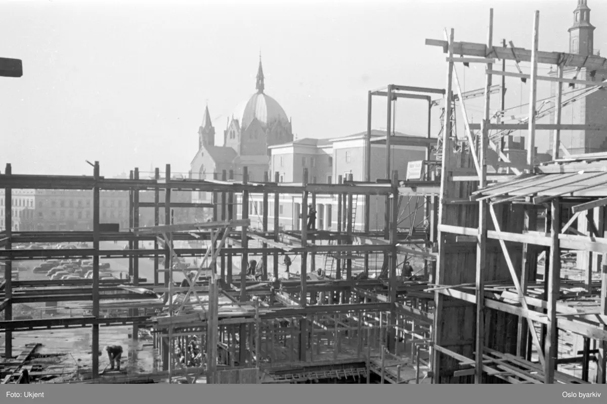 Byggeplass, Oslo hovedbrannstasjon, reisverk, stillas. Deichmanske bibliotek og Trefoldighetskirken i bakgrunnen. Ved daværende Henrik Ibsens gate, nåværende Hammersborggata.
