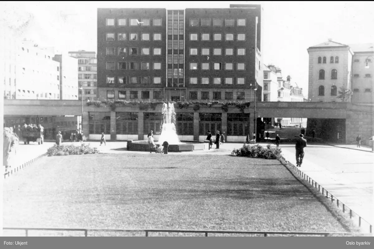 Arne Garborgs plass brosteinbelagt med grøntanlegg og fontene. Hovedbrannstasjonen (tårn for slangetørk) med garasjeanlegget (1939). Henrik Ibsens gate (nå Hammersborggata) og Hospitalsgata (høyre) fra Akersgata, nedsenket under Grubbegata. Fengselsbyggningen til Møllergata 19 (revet 1981) mot Grubbegata til høyre.