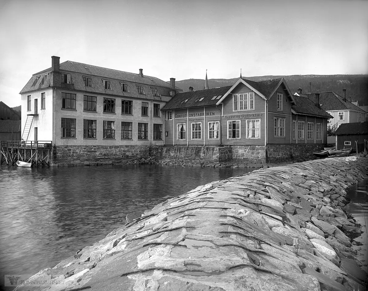 Ved Moldeelvas utløp ca 1915..Confectionsfabrikken Superbs lokaler sett fra sør Oscar Hanssen, Herre og Gutteklær -engross-.