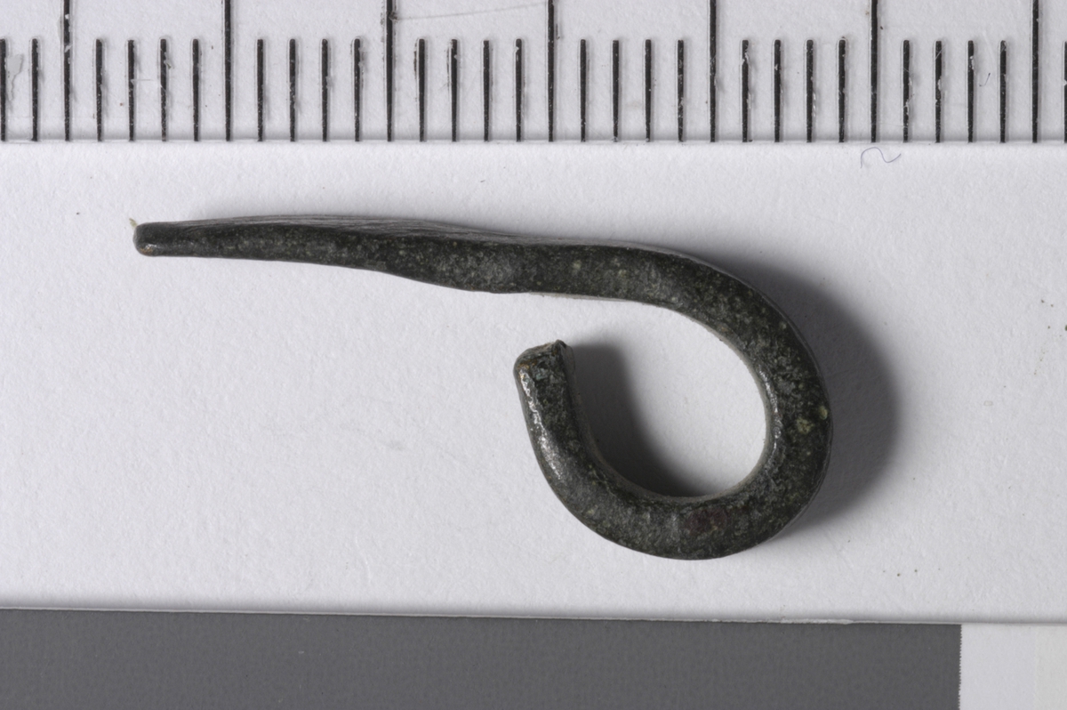 MALV: L. 22, B. 3, 5, T. 1, 9 MM, 3, 5 MM BREDT BÅND SOM ER OMBØYET TIL ØYE I ENE ENDENOG AVSMALNET MEN BUTT AVSLUTNING I ANDRE ENDEN. 