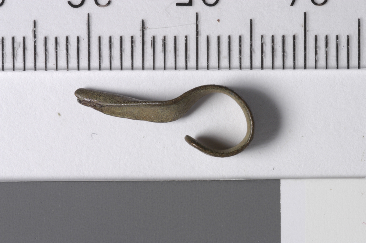MALV: L. 19  B. 4 MM, 4 MM BREDT METALLBÅND OMBØYET TIL ØYE I ENE ENDENOG SAMMENPRESSET TIL SPISS I ANDRE. 