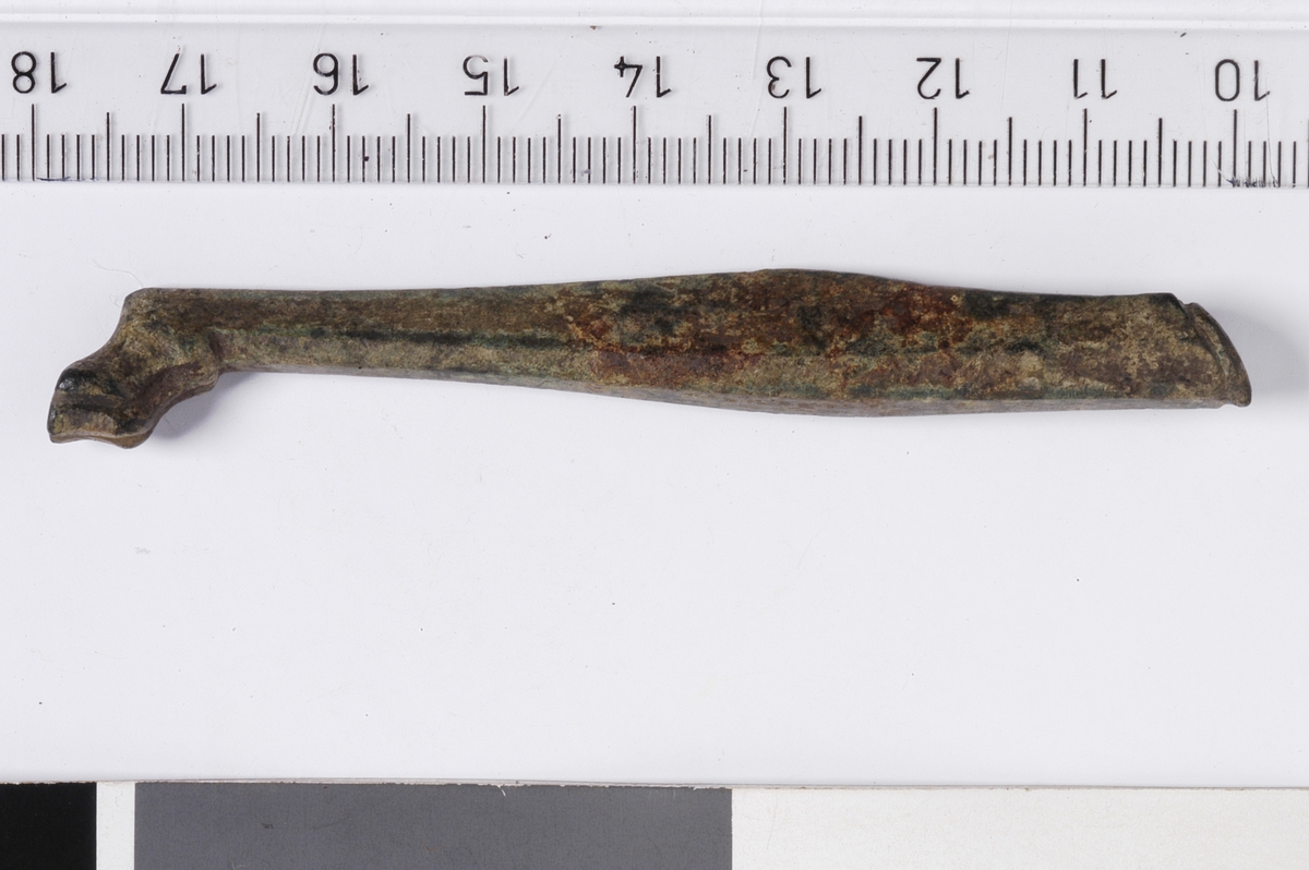 MALV: L. 79 MM, ST. TYKK. CA. 10 MM, AVLANGT, FEMKANTET. FORM SOM ET DYREBEIN MED "TÆR"OG FORTYKKELSE FRA MIDTEN OG OPPOVER SOM SKAL ANTYDE LEGGMUSKLER. SKRÅTT AVSKÅRET ØVERST. HER ER DET FILT UT ET SPOR LANGS KANTEN, ANTAGELIG EN SLAGS FESTEANORDNING. 