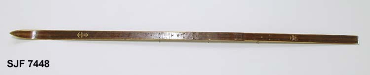 Enkelt turlangrennski uten binding. Skia er 208 centimeter lang. Bredden fremst, der kurven mot tuppen starter, er 5,9 centimeter. Ved bindingsstedet er bredden 4,9 centimeter. Bakerst er bredden 5,5 centimeter. Skia er med andre ord noe innsvingt (konkav) i lengderetningen. Tjukkelsen der hvor kurven mot tuppen starter er 0,6 centimeter. På midten, der hvor bindinga skulle monteres, er tjukkelsen 2,5 centimeter. I den bakre enden, som er noe oppsvingt, er tjukkelsen om lag 0,7 centimeter, cirka 5 centimeter framfor endebeslaget. Langs midtaksen på undersida (sålen) er det høvlet ei styrerand, en cirka 1,0 centimeter bred hulkil. Langsmed sålens ytterkanter har skia 6-7 millimeter brede hardvedkanter, lagd av lignostone, bøkeved som er presset under høyt trykk, og som her framstår som mørkere enn det øvrige treverket i skiene. Oversida av skia er brunlakkert, med unntak av smale faser langs sidekantene, Giveren mener at dette er ei «Toppen-ski» fra Gjøvik skifabrikk, men et klistremerke med en innringet «K» kan peke i andre retninger. Bakskiene er merket med et klistremerke der det står «MADE IN NORWAY». Framfor bindingsfestet er sifrene «210» (skilengden) og «2563» (muligens et priduksjonsnummer) innstemplet.