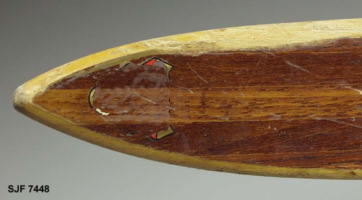 Enkelt turlangrennski uten binding. Skia er 208 centimeter lang. Bredden fremst, der kurven mot tuppen starter, er 5,9 centimeter. Ved bindingsstedet er bredden 4,9 centimeter. Bakerst er bredden 5,5 centimeter. Skia er med andre ord noe innsvingt (konkav) i lengderetningen. Tjukkelsen der hvor kurven mot tuppen starter er 0,6 centimeter. På midten, der hvor bindinga skulle monteres, er tjukkelsen 2,5 centimeter. I den bakre enden, som er noe oppsvingt, er tjukkelsen om lag 0,7 centimeter, cirka 5 centimeter framfor endebeslaget. Langs midtaksen på undersida (sålen) er det høvlet ei styrerand, en cirka 1,0 centimeter bred hulkil. Langsmed sålens ytterkanter har skia 6-7 millimeter brede hardvedkanter, lagd av lignostone, bøkeved som er presset under høyt trykk, og som her framstår som mørkere enn det øvrige treverket i skiene. Oversida av skia er brunlakkert, med unntak av smale faser langs sidekantene, Giveren mener at dette er ei «Toppen-ski» fra Gjøvik skifabrikk, men et klistremerke med en innringet «K» kan peke i andre retninger. Bakskiene er merket med et klistremerke der det står «MADE IN NORWAY». Framfor bindingsfestet er sifrene «210» (skilengden) og «2563» (muligens et priduksjonsnummer) innstemplet.