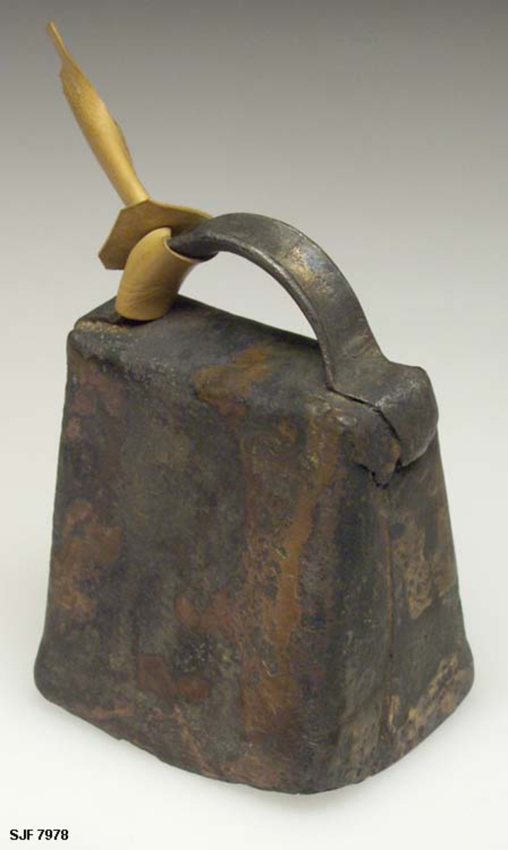 Bjelle, muligens ei lita kubjelle, som er lagd av ei kobber- eller messingplate som er bøyd slik at den har fått et noenlunde rektangulært tverrsnitt, rikrignok med noe avrundete hjørner. Bjella blir stadig videre mot åpningen i den nedre enden, der yttermålet  er 7,5 X 5,8 centimeter. I den øvre enden er yttermålet 7,3 X 2,9 centimeter. Over overenden er det montert ei bøyle med buet tverrsnitt som skulle festes i en klave som hang rundt halsen på det dyret med ønsket å kunne lokalisere ved hjelp av lyden fra bjella. På undersida er det ei jernbøyle hvor det er festet en «kolv» eller «bell» - en jerntein som henger og dingler inne i bjellekammeret, og som setter igang vibrasjoner som genererer lyd når en fortykning i ytterenden treffer den innoverfalsete ytterkanten på bjellekammeret.

Her er bøyla på ovesida av bjella påsatt en liten stropp av lysebrunt lær. Stoppen er antakelig påsatt av en samler som har hatt denne bjella som prydgjenstand i hjemmet sitt.