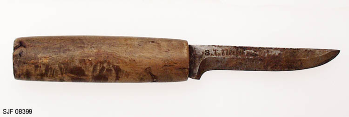 Tollekniv uten slire, lagd av smeden Svein Svimbil (1888-1987) fra Tinn Austbygd i Vest-Telemark. Kniven er 19,5 centimeter lang. Knivbladet utgjør 9,1 centimeter av dette lengdemålet. Bladet er 2,1 centimeter bredt bakerst ved brystningen, men egglinja er slipt såpass mange ganger at bladbredden på midten er bare om lag 1,5 centimeter. Bladtjukkelsen er om lag 4 millimeter ved brystningen, men bladet tynnes gradvis framover mot knivspissen. Bladryggen er forholdsvis rett, riktignok en aning konvekst buet i den fremre enden, der sidekantene er avfasete. Smeden har plassert stempelet sitt - «S.T. TINN» bakerst på det som når kniven holdes i arbeidsstilling er høyre bladside. De nevnte initialene refererer til Svein Tverberg, som var det navnet smeden brukte før han kjøpte småbruket Svimbil.