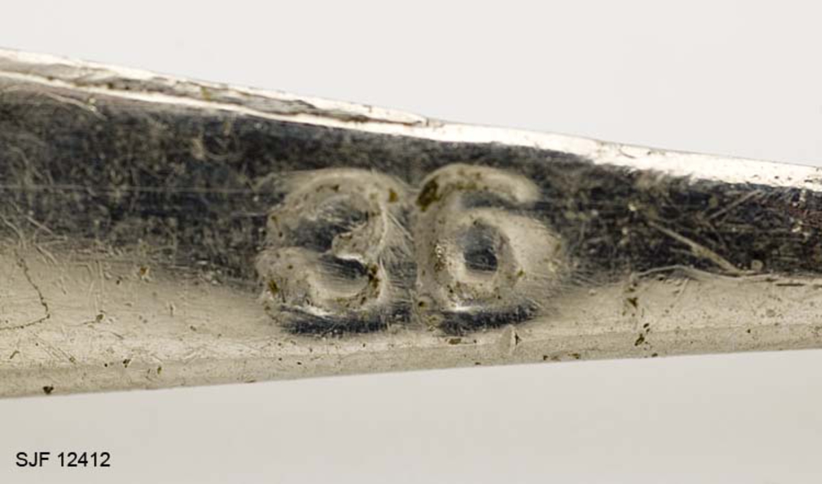 Svakt bøyd trekantet, bananformet, pilk med treblekrok (trippelkrok). Trippelkroken er festet til en ring som ser ut til å være loddet. Kroken er trukket med en plaststrømpe (gummislange) som er splittet mot krokspissene. Pilken har en ring for senefeste i bakkant. Uten at det er bekreftet, antas det at pilken er en såkalt "Svenskepilk".