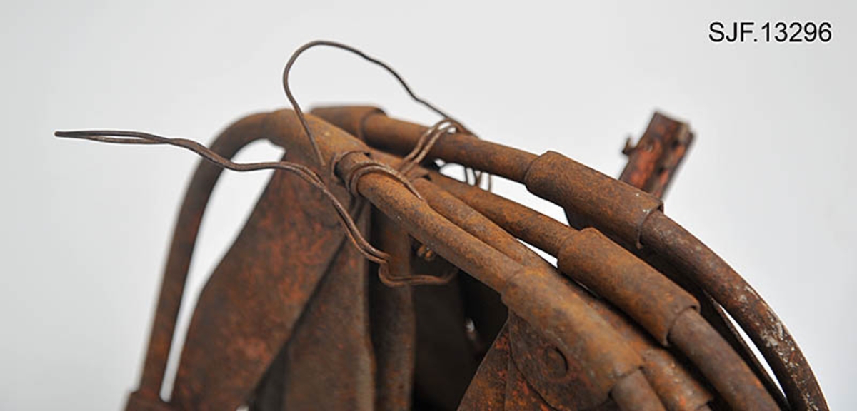 Trugesett for hest, altså fire stykker.  Trugene er lagd av jern.  Rammene er lagd av rør med cirka 1,1 centimeters diameter.  Disse rørene er bøyd i tilnærmet rektangulær form, men med noen avrundete hjørner.  Hver truge er om lag 30 centimeter lang og 24,5 centimeter bred, og har dermed ei bæreflate på drøyt 700 kvadratcentimeter.  Formen holdes stabil ved hjelp av jernband som er bøyd rundt rammerørene og klinket sammen.  To slike band går på tvers av trugene (i bredderetningen) mens det i lengderetningen er lagt band i M- eller W-mønster (avhengig av hvilken veg trugene holdes, M hvis de betraktes skrått bakfra).  De bakerste tverrbandene har kanter som er bøyd oppover, antakelig for å kunne tjene som anlegg for hakene på skogshestens vintersko.  Gjennom de brede tverrbandene noe lengre fram på trugene er det ført jernører med gjennombrutte hull for hengslingslekker for bøyler som ble lagt over hornveggene på hestens framføtter. Den ene bøylehalvdelen har T-formet tverrsnitt med hakk i overkant og lærfôringer på undersida (festet med ståltråd). Ei truge mangler slik fôring, de andre er stive og sprø etter mange års tørk uten tilførsel av nye fettstoffer. Den andre halvdelen av bøylemekanismen består av en lang, buet kjettinglekk med ei dreibar klype med ei gjennomgående nagle like bak hengslingspunktet. Denne nagla føres ned i ett av hakkene på ryggen av den andre bøylehalvdelen, hvoretter endeleddet presses ned. Dermed låses truga godt til foten på hesten. Under tverrbandene bøylene er festet i er det montert jernstag med T-formet tverrsnitt på tvers av trugenes lengderetning. Disse komponentene skulle antakelig redusere faren for at trugene skled på vinterføre. De nevnte tverrstagene er for øvrig festet med kvadratiske muttere på endetappene av «jernørene» som bøylene på oversida av trugene er hengslet til.  På jernet kan vi se spor av oransje lakk, men fargestoffet er i ferd med å bli fortrengt av gravrust. Trugetypen later til å være en serieprodusert artikkel. De brede tverrbandene på to av trugene er merket «ØR» i prikket utførelse. Trugesettet ble levert til museet sammenbuntet med en ståltråd, antakelig slik de har vært oppbevart siden sist de var i bruk.  Ifølge siste eier, Magne Ottershagen fra Styggberget i Elverum, skal dette ha vært vinteren 1953-54.

I Sverige kalles denne trugetypen «norsktrampa», hvilket vel indikerer at det må ha vært en norsk produsent som har eksportert slike truger til nabolandet.