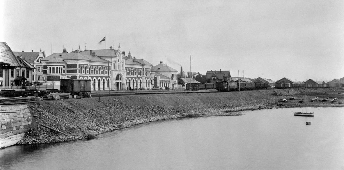 Hamar jernbanestasjon, her sees alle de tre stasjonsbygningene. Den første jernbanestasjonen fra 1862, Grundsethbanen, kan ses helt til venstre og den andre satsjonen fra 1880 Eidsvollbanen. I midten den siste bygningen som sto ferdig i 1894 Hamar - Trettenbanen, jernbanefylling, 
