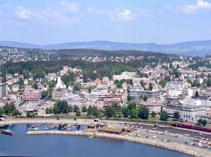 Hamar, flyfoto, bypanorama, sentrum, Midtbyen, Strandgata, Strandgateparken, Hamarbukta, parkeringsplass på åttemetersplanet, Hamar småbåthavn, molo, Busy Butler åpnet servering 22. oktober 1968, drive-in-restaurant, Shell bensinstasjon kalt Busy Service,