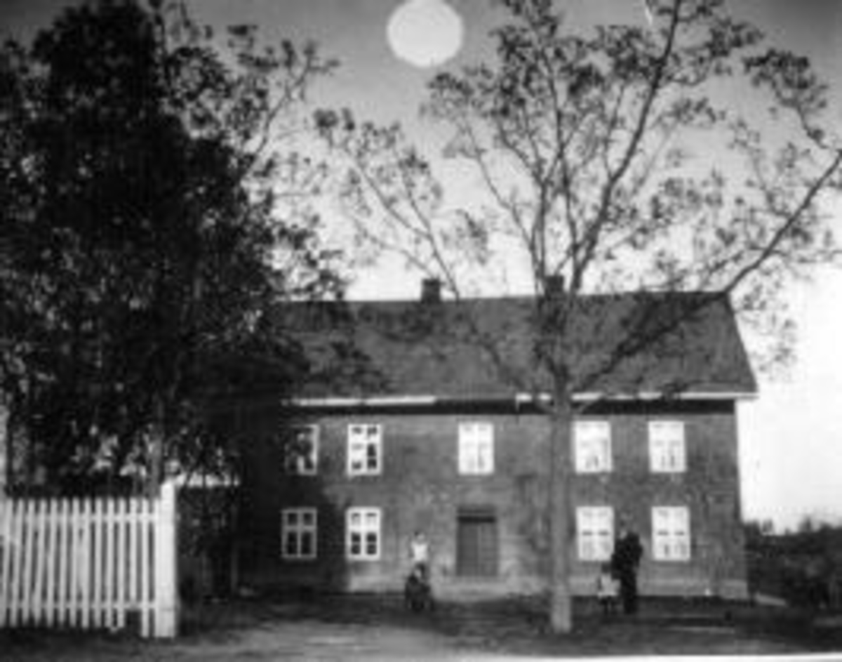 Eksteriør. Hovedbygningen på Mellom-Kise, med hage og tuntre. Haugen med datter Anna Marie (1910-1992) og ukjent. "Solen" over huset er antagelig påført fotoet.