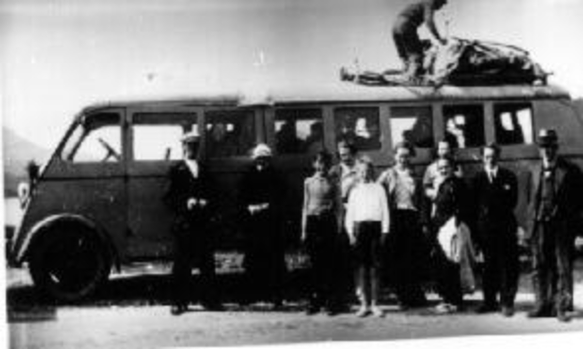 Busstur. Sykler og bagasje festet på busstaket. Gruppe mennesker foran bussen, flere i bussen.