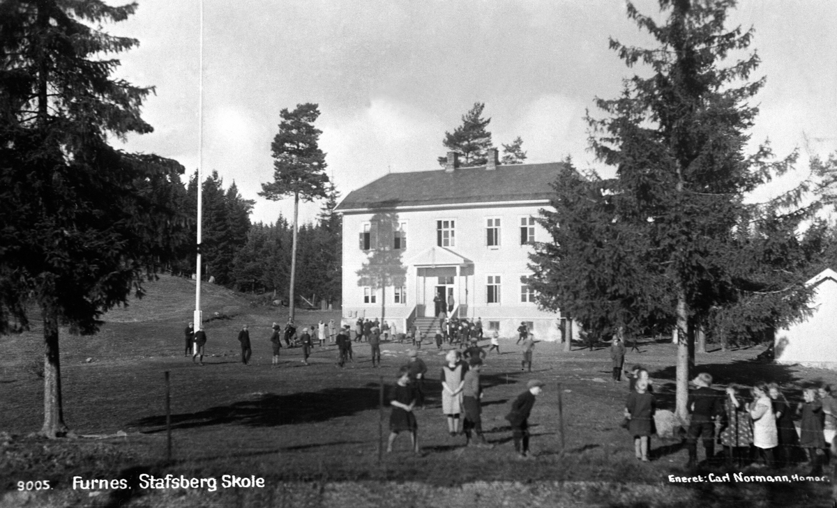 Postkort, Stafsberg skole, Furnes. Barn leker på skoleplassen. "Stavsberg skole 1920". Gamle Stavsberg skole sto ferdig i 1918. Rundt 1930 var Stavsberg skole største skolen i Furnes Kommune på grunn av stor boligbyging på Ajer som den gang lå i Furnes. Under okkupasjonen ble skolen beslaglagt av tyskerne og brukt som en del av Stavsberg militærleir. Ved frigjøringen i 1945 var den så ødelagt at den ikke kunne brukes mer. Noen år senere ble den revet. "