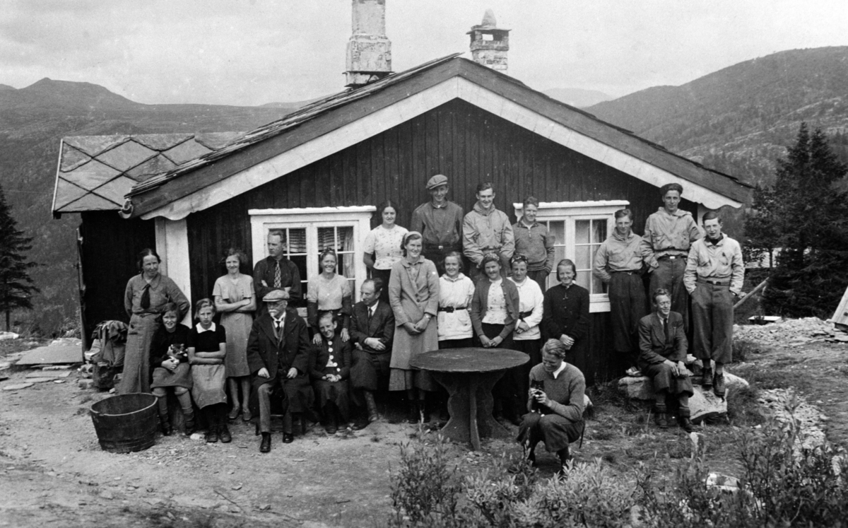 Brøttum kristelige ungsdomsforening på besøk på Mysusæter, Rondane.. Fra sogneprest Thomas Hauges hytte på "Ellehaugen". Han ble sogneprest i Sel i 1913 og i Brøttum i 1925. Han fikk bygslet en hyttetomt i allmenningen i 1915 som han senere kjøpte. Bildet er ganske sikkert tatt ved et besøk av Brøttum kristelige ungdomsforening, men det er også mange av Hauges familie på bildet. 
Fra venstre(bakre rekke): Else Hauge, f. Bryn, Kirsten Hauge, ukjent, Kari Hauge, Johannes Hauge, Rut Hauge, Gerda Kinde, Per Mæhlum, ukjent, Gunnar Solli. Foran fra venstre: (eldre mann)Fredrik Gad, ukjent, Thomas Hauge, Arnlaug Mæhlum, ukjent, Julie Kinde, ukjent, ukjent. Tre menn stående på høyre side: Peder Skjæret, ukjent, ukjent. Sittende foran: Nils Hauge. Sittende helt foran med katt på fanget: Kåre Mæhlum.