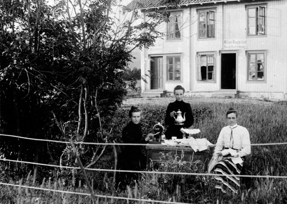 3 damer drikker kaffe i hagen. Oline Rognstad gift Aas med to sydamer. eksteriør Negård, Olsengården, posthus her 1915-20. I huset bak Arnt Aas skotøyforretning, Oline Rognstads moteforretning, Nygata, Brumunddal.