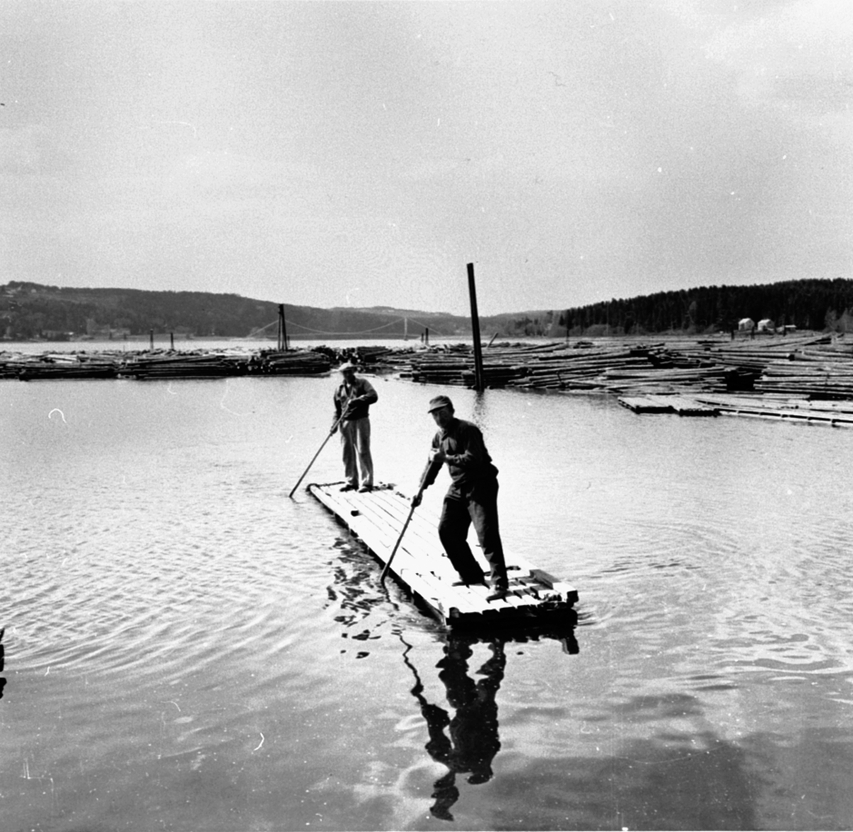 2 menn på flåte ved strandsaga, Berger Langmoen A/S, Brumunddal. Raagnar Bakken foran, Gunvald Asmundsen bak.