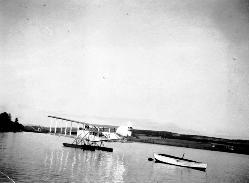 Leif Lier (1895-1929) sitt sjøfly N-26 uten for Odden, Eskerud, Helgøya. Neslandet og Nes kirke i bakgrunnen.