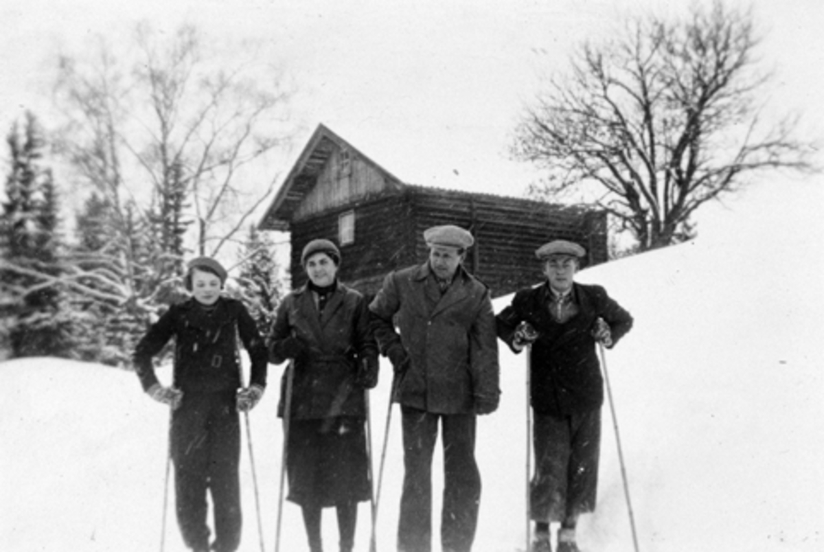 Skitur foran et av stabburene på Bjørnstad, Nes, Hedmark. Folkene er trolig fra venstre Ingrid (1922-1946), Anna Margrethe (1892-1980), Asbjørn (1882-1967) og Erling Feiring (1915-1988).