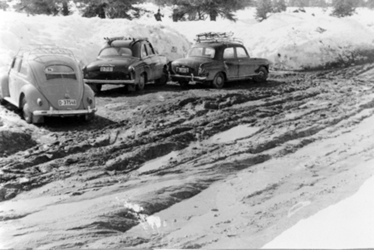 Ljøsheim påsken 1962. Vegen til Ljøsheim har gått i oppløsning, telehiv, tre parkerte biler.