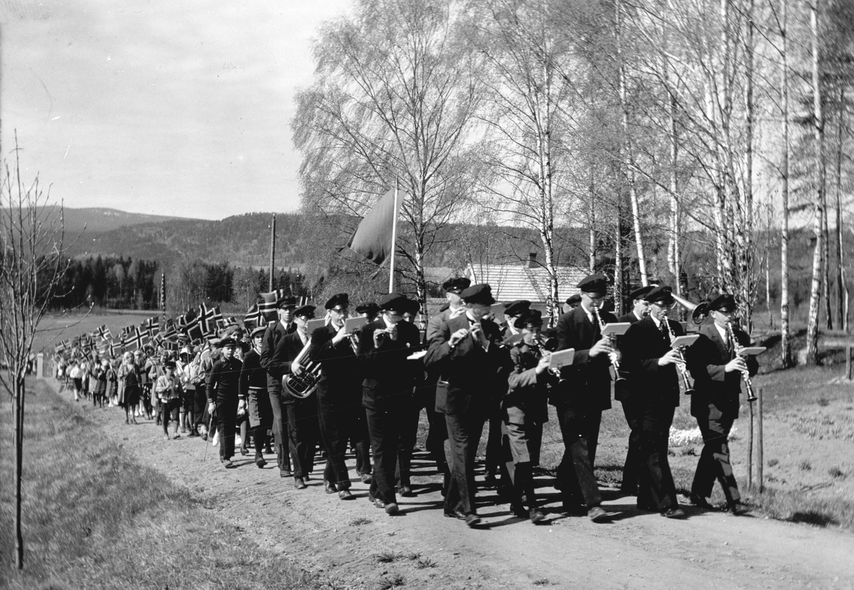 Moelv Musikkforening marsjerer opp vegen til sykehuset, Ringsaker Sykehjem. 
17. mai-tog ca. 1937-1938