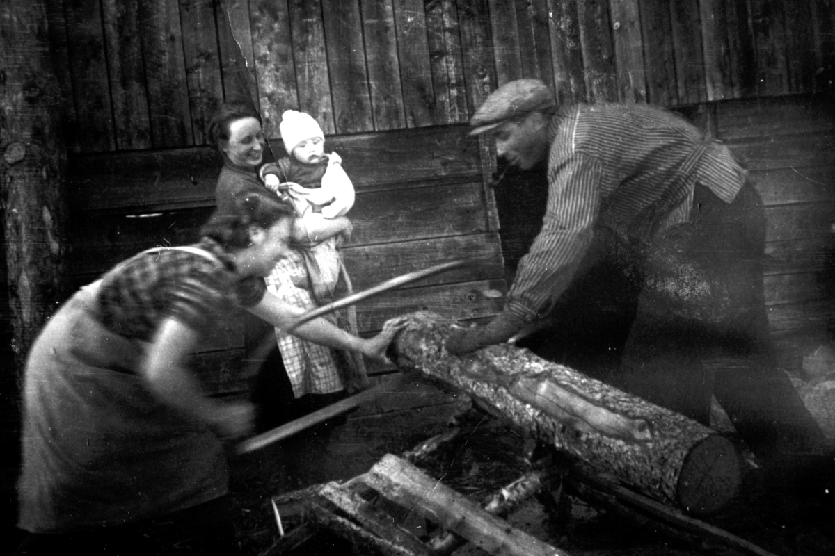 Paula Solbakken og Håkon Nordsveen sager ved, brensel, Borghild Solbakken med Håvard ser på. Solbakken ca. 1941