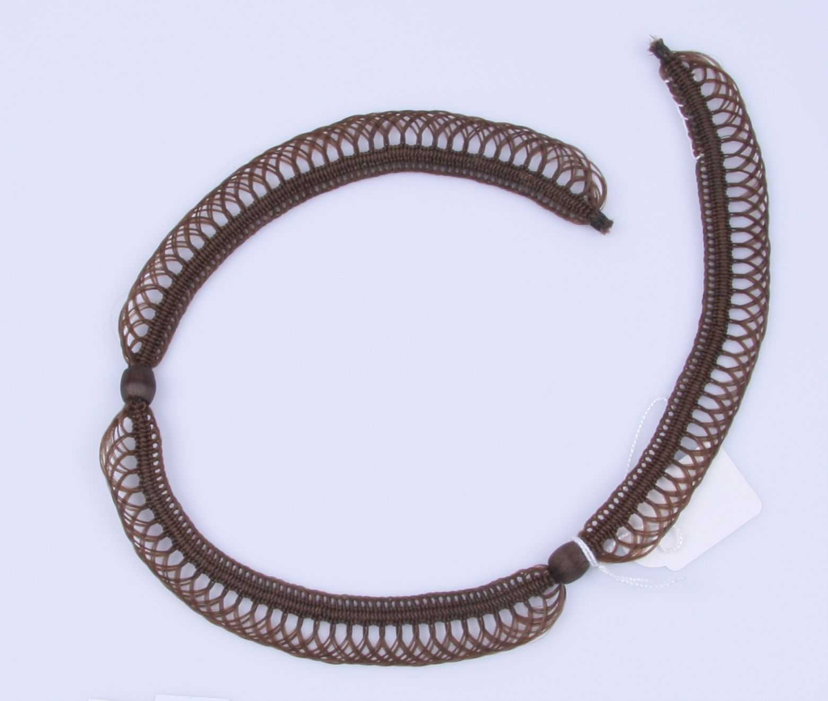 Halssmykke i kragefasong, ytterst med en gjennombrutt kant, innerst en fastere kant, begge holdt sammen på to steder av runde hårtrukne perler. Lås mangler.