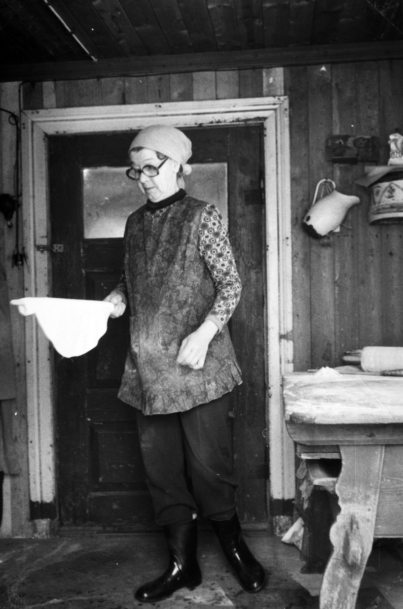 Lefsebaking i størhuset i Fossengen nordre, Vallset i desember 1978. Oline Rønningsbakken kjevler ut deigen på det gamle kjøkkenbordet fra 1800-tallet som engang ble plassert i dette rommet i størhuset. (Registrert av Oddmund Rønningsbakken)