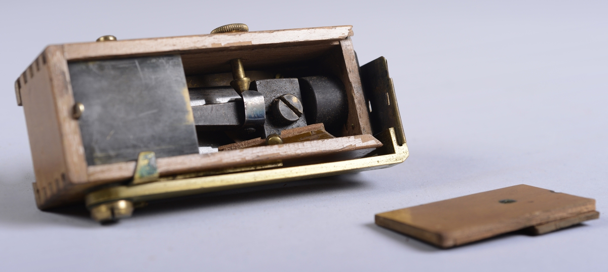 Måleinstrument oppbevart i rektangulært etui av skinn. Etuiet har reim og metallspenne for feste av lokket på front, og hemper på sidene.

Selve treesken:  10*3*4 cm.  Lengde på messingdelen:  10 cm.  Bredde på messingdelen:  1 cm.  Messingskiva fremme:  3*3 cm.  Etuiet:  6*10,5*4 cm.  Etui-lokket:  4,5*5,5*6,5 cm.