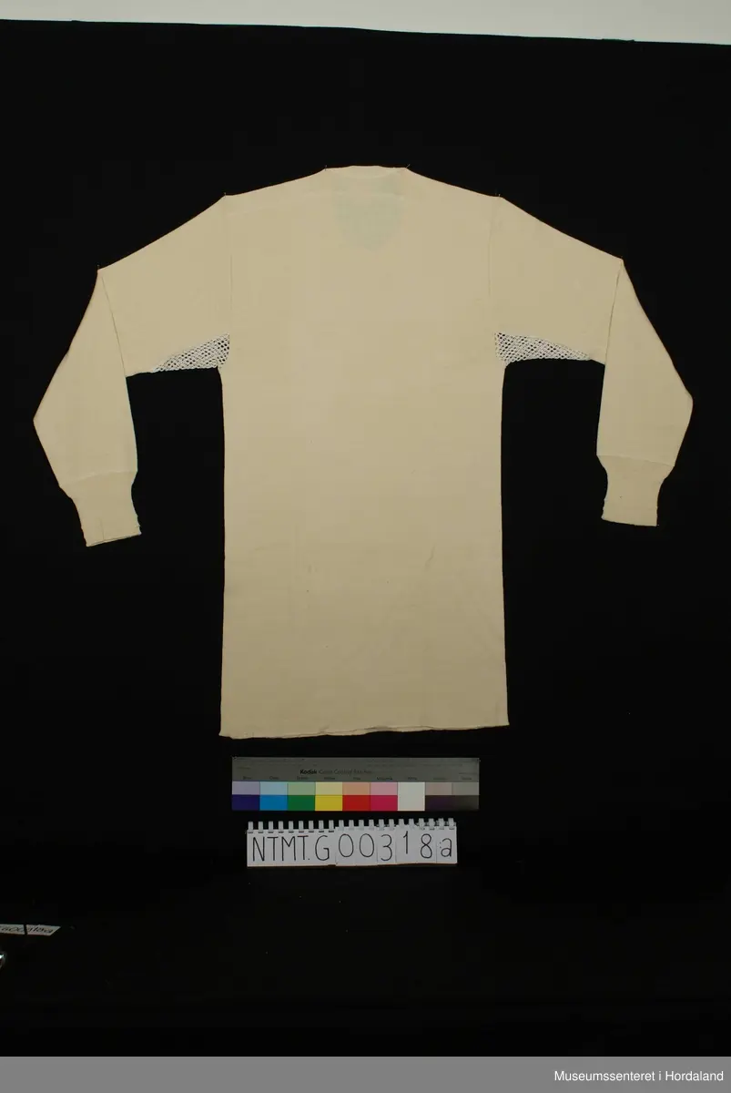 Lange ermer med brotavslutning, rund hals, skulderstykke, kile med helsetrøyestoff under ermer.