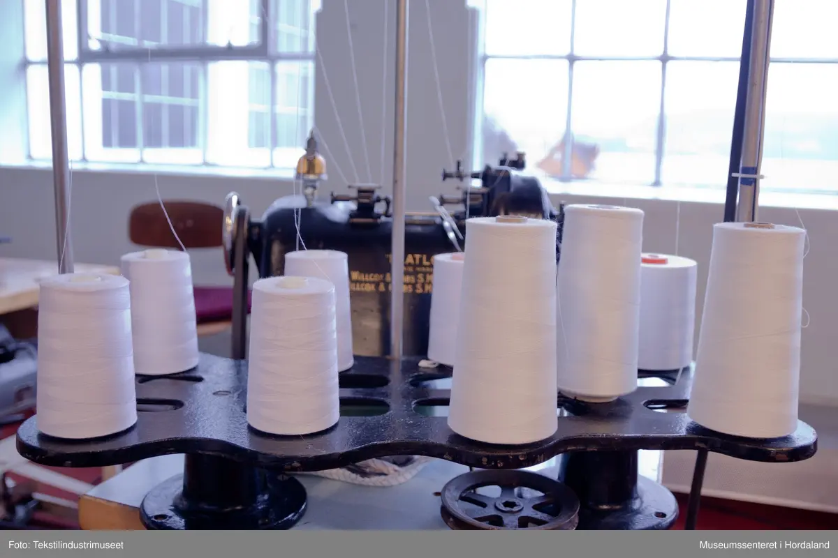 Flatlock-symaskin i svartmåla støypejern og med halvautomatisk oljing. Maskina er montert på eit Juc-bord og har Singer-motor (truleg ikkje original).

Motor: Singer alternating current electric transmitter. No. K 692357 R
Volts: 210-230.