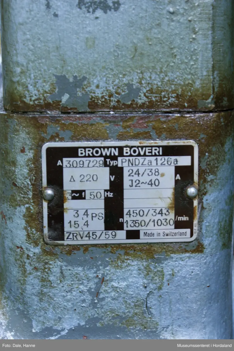 Elektrisk ringspinnemaskin (1958) frå det sveitsiske selskapet Rieter. Øvst på maskina plasserer ein spolane med forgarn frå kardemaskina. Reint teknisk er det tre hovudelement i spinninga:  forgarnet blir strukke, tvista (snodd) for å få meir styrke, før det ferdige garnet blir oppvikla på ein spole eller 'spinnepipe'. Tråden går under eit transporthjul i tre, gjennom støypte løpegangar og vidare nedover: Garnet blir snodd ved at garnet passerer ein løpar som beveger seg på ein ring, før det blir samla på ein sylindrisk metallspole. Det er ei rekkje små støvsugarar langs heile maskina, små røyr som stikk ut over spolane. Desse syg til seg støv og/eller tråden viss den ryk, for å unngå at den kjem inn i maskina. Trådrestar og støv blir samla opp i eit oppsamlingskammer på venstre sida av maskina. Der er det òg ein målar som måler kor mykje maskina spinner.

Drivverket og ein stjernemotor sit på høgre sida av maskina. På sida står det "Rieter" i raudt, og det er to målarar som måler omdreiingar/hastigheit på maskina. Det er ei rekkje med 136 koner på kvar side. Maskina kan byggjast på i seksjonar, og slik utvidast etter behov, noko som er vanleg for spinne- og spolemaskiner.