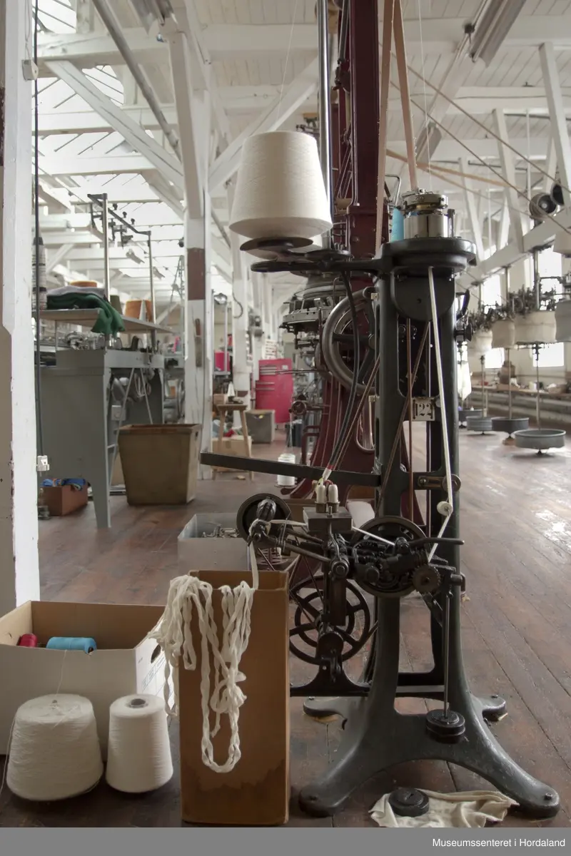 Rundstrikkemaskin med liten diameter frå Schubert & Saltzer Maschinenfabrik i Chemnitz i Tyskland, brukt på Salhus Tricotagefabrik utanfor Bergen. Maskina har berre 16 nåler, to trådar og ein trådførar, og vart truleg brukt til å strikke stay-band som gjorde saumane fastare.

Den har eit handtak på eine sida som ein kan bruke til å sveive maskina manuelt, og eit hjul på denne sida det maskina er kopla til reimdrifta i taket. Maskina har eit lite strykejern som stryk den ferdigstrikka "pølsa" etter kvart som den vert strikka. Strykefunksjonen er kopla til med elektrisk stikkontakt. Er dette ei forbetring som har komme i ettertid? Det kan òg tenkjast at det har vore ei rulle festa til maskina som rulla opp bandet direkte.