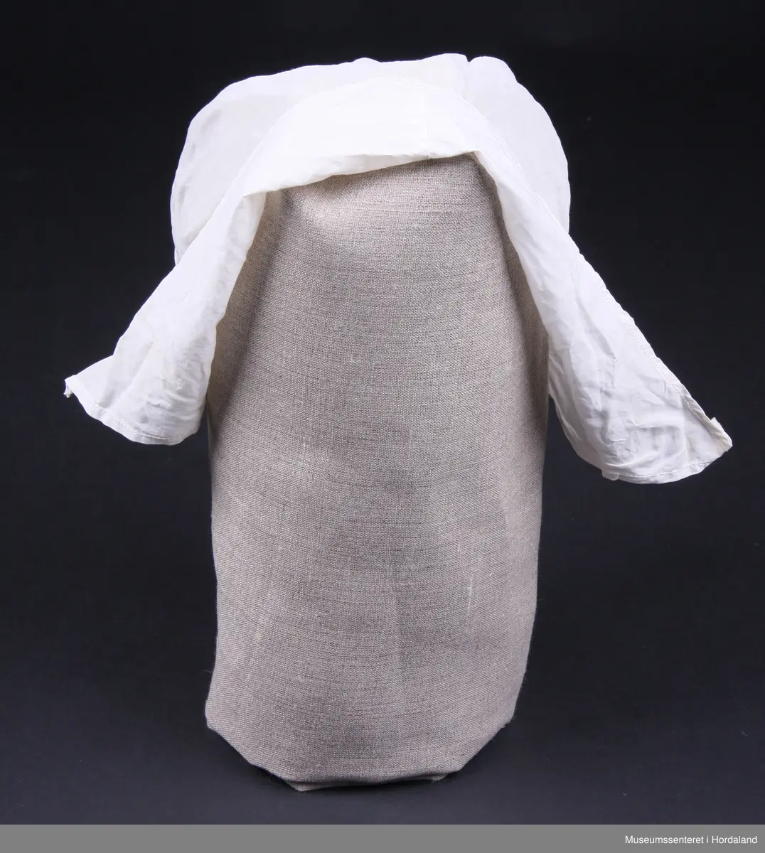 Svært tynt bomullslerret og brem i litt tjukkare lerret ( men framleis tynt - batist).
Strikk bak i nakken. Sølve hua er i eit stykke, medan bremmen har saum midt oppe på hovudet.Smal maskinsydd fall på bremmen.