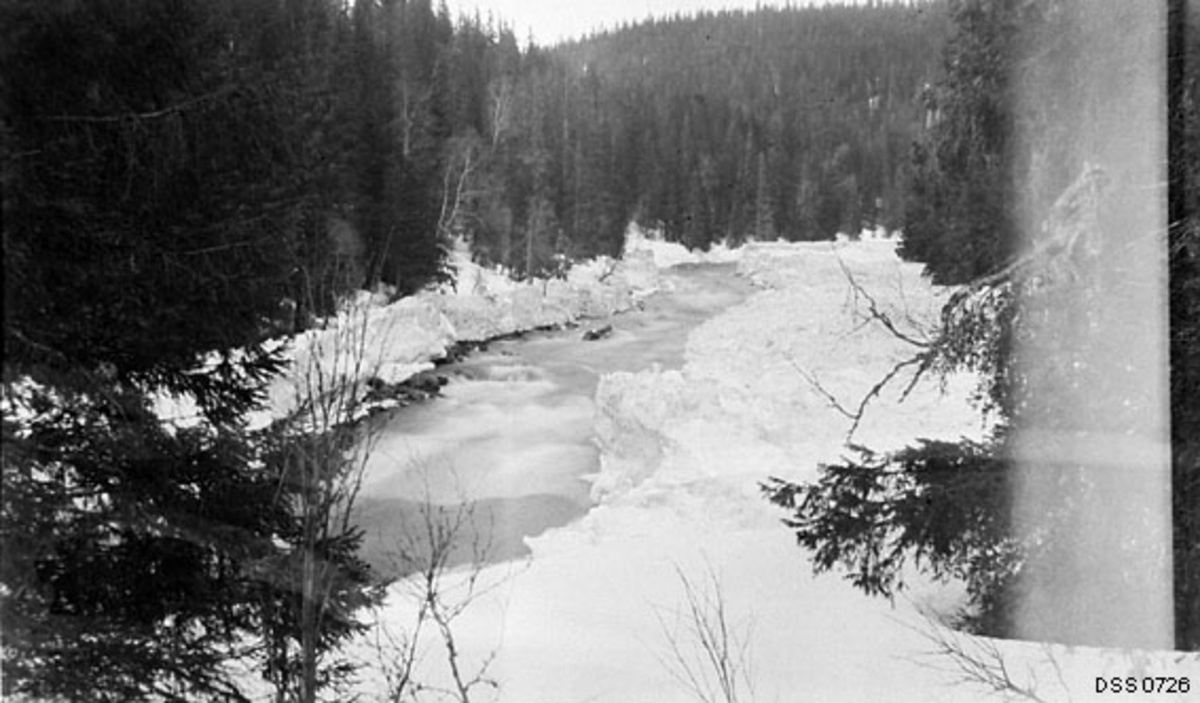 Grønfjellåa seinvinters.  Elva går forholdsvis strid mellom snø- og isskavler langs breddene.  På åsene langs vassdraget står det tett granskog. 