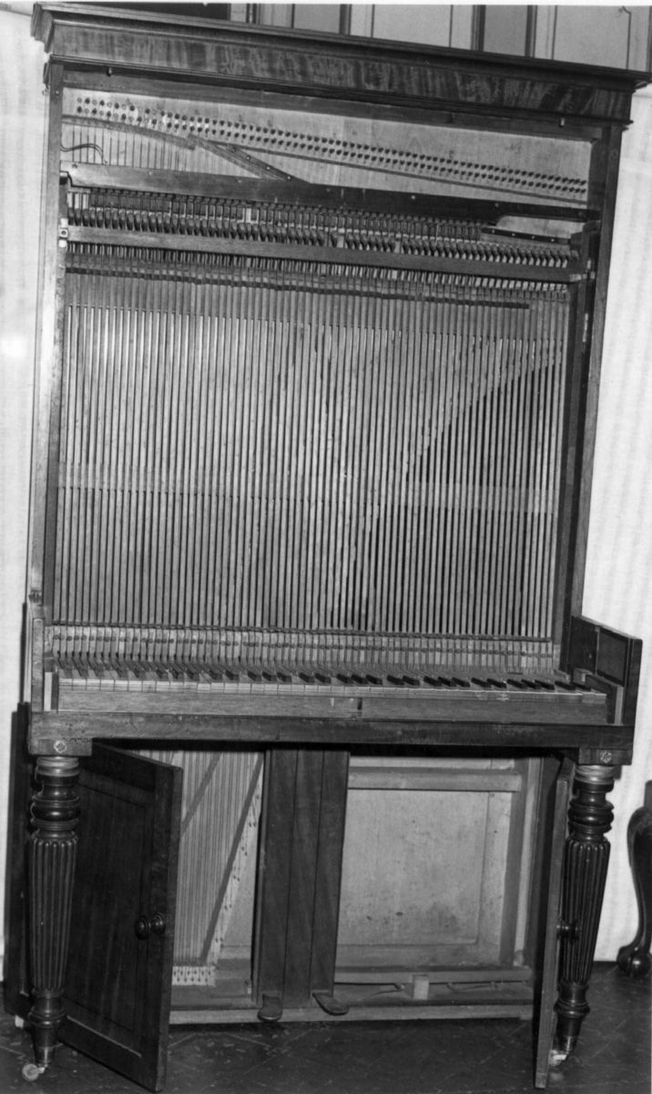 Instrument med omfang: FF - f'''' (6 oktaver).

Firkantet korpus med to bein framme og en rød tekstilavdekking på forsiden. Finer sannsynligvis mahagoni. Lokk tredelt med to knapper og mørk treinnlegg. Når lokket åpnes kan to halvsirkelformede plater felles frem som hyller for lysestaker.
Under klaviatur to dører foran klangbunnen.
