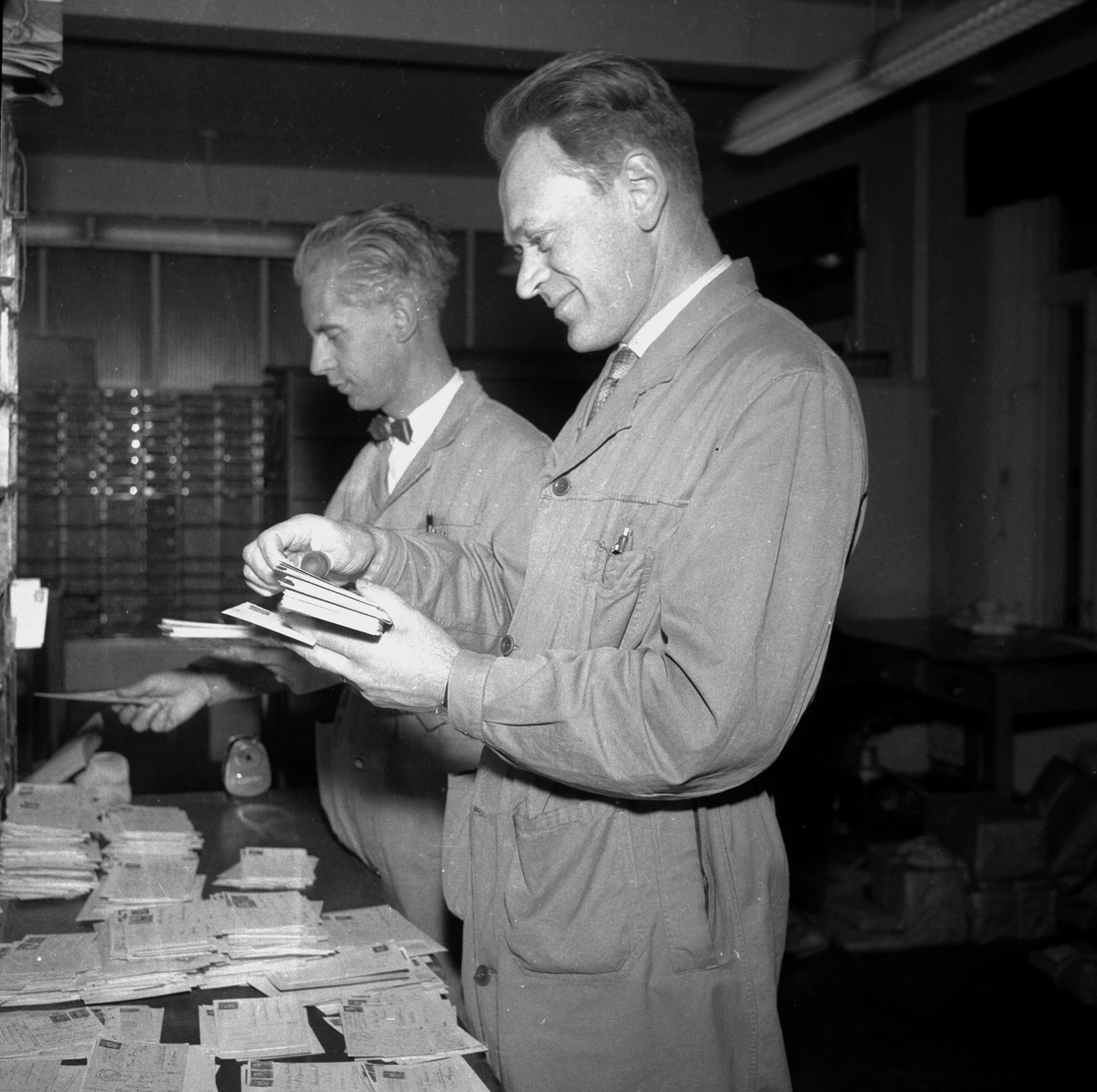 POSTSORTERING HAMAR POSTKONTOR. KNUT SEKKELSTEN (. T. V. ) OG JOHAN SLIND. STED: POSTKONTORET KOMMUNE: HAMAR DATO:??. 12. 1960 FOTO:EGIL M. KRISTIANSEN 