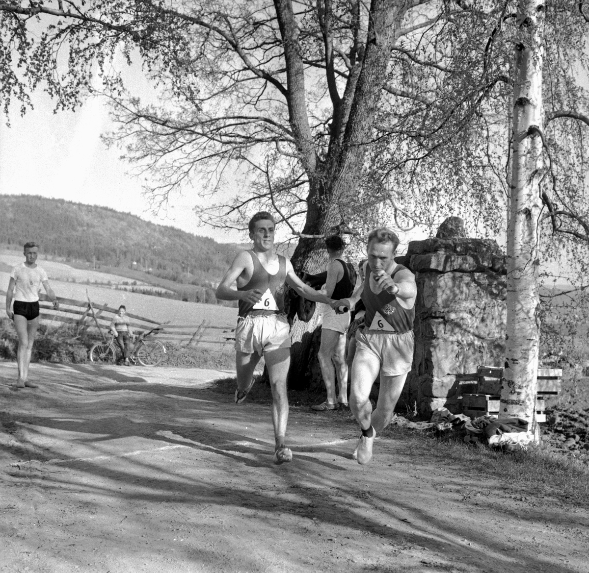 VELDRESTAFETTEN. HAMAR IL. OVE HELLAND PEDERSEN OVERTAR PINNEN FRA BJØRN WESTMO. FRIIDRETT; STAFETT;LØP. STED: VELDROM. KOMMUNE: RINGSAKER DATO:18. 05. 1959 FOTO: EGIL M. KRISTIANSEN 