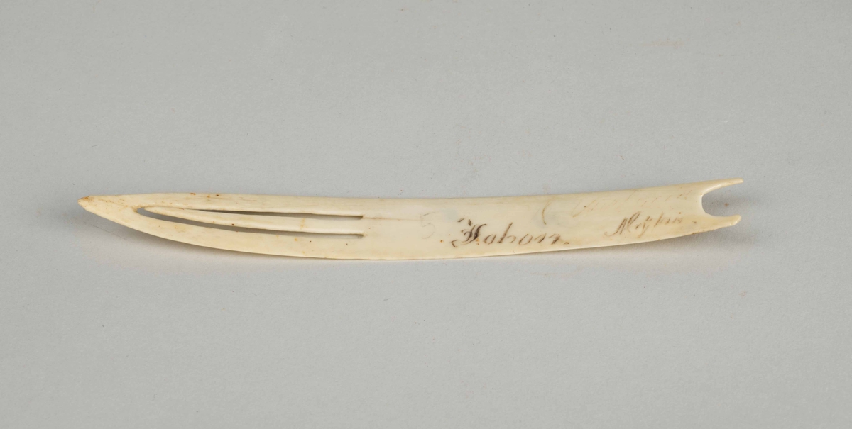 Avlang, spisset i den ene enden, buet i den andre. Flat. Har inskripsjon som er vanskelig å tolke, lar seg ikke avskrive.