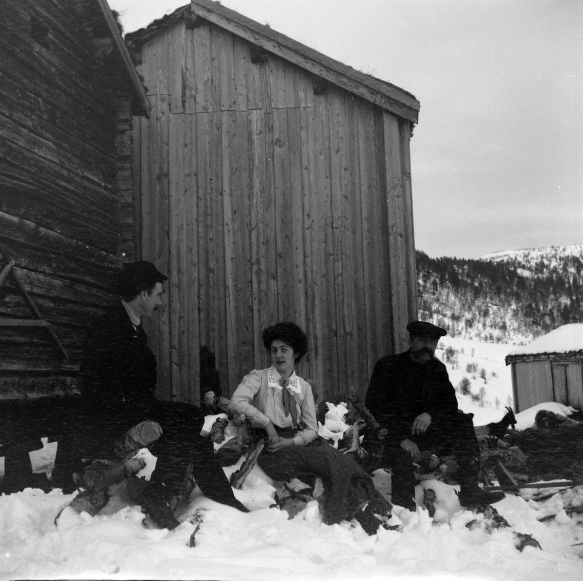 Fra Songli. Matty Christiansen og to menn på en vedstabel.